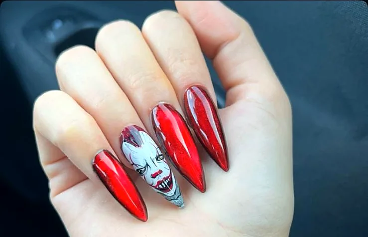 Unghie a stiletto rosse con un volto dipinto su un dito